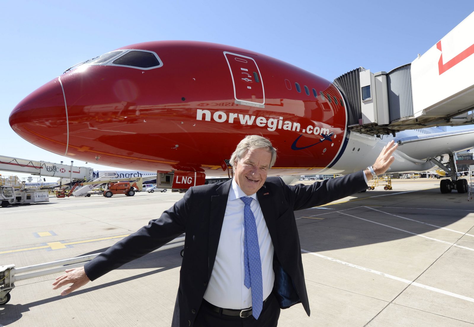 a man in a suit standing in front of a red airplane
