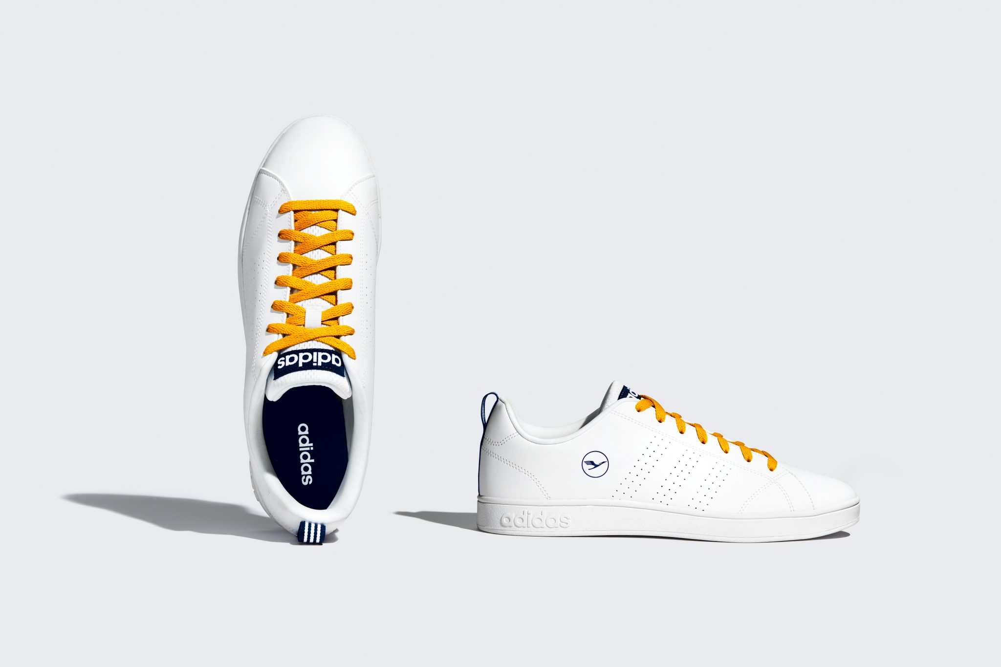 a pair of white shoes with yellow laces