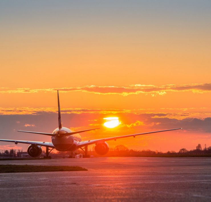 an airplane on the runway at sunset