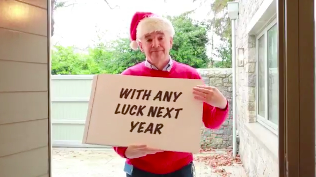 a man in a red sweater and santa hat holding a sign