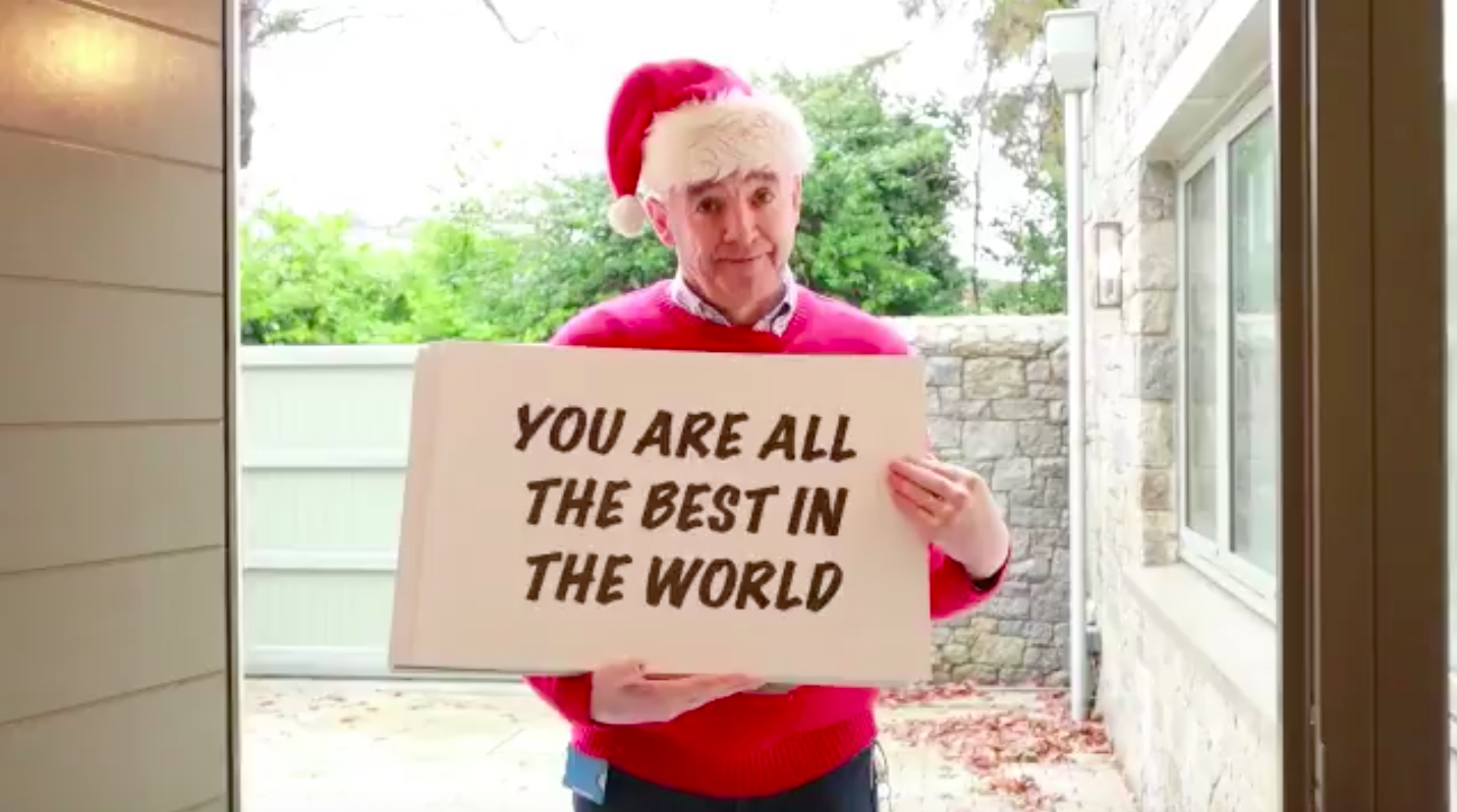 a man in a red sweater and santa hat holding a sign