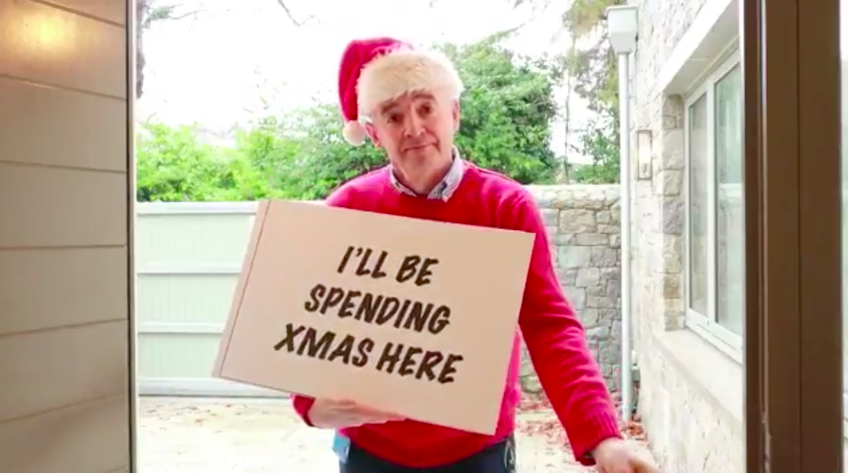 a man in a red sweater and santa hat holding a sign