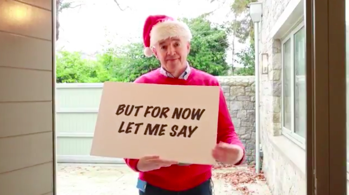 a man in a red sweater and santa hat holding a sign