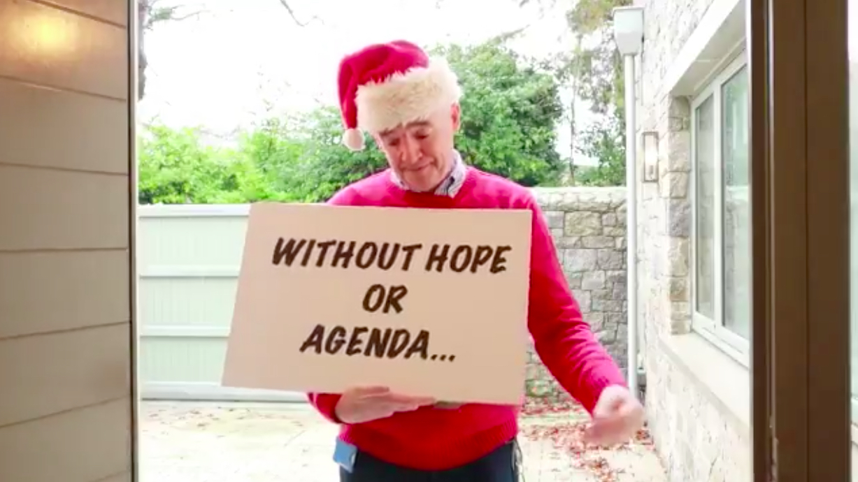 a man in a red sweater and santa hat holding a sign