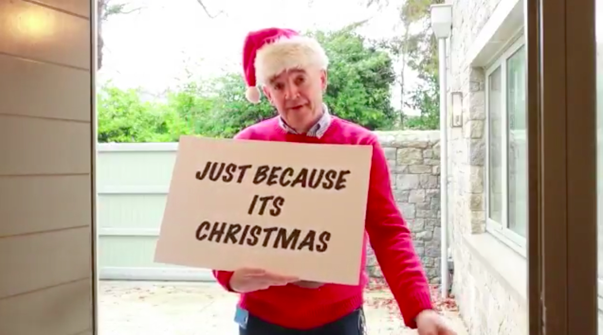 a man in a red sweater and santa hat holding a sign