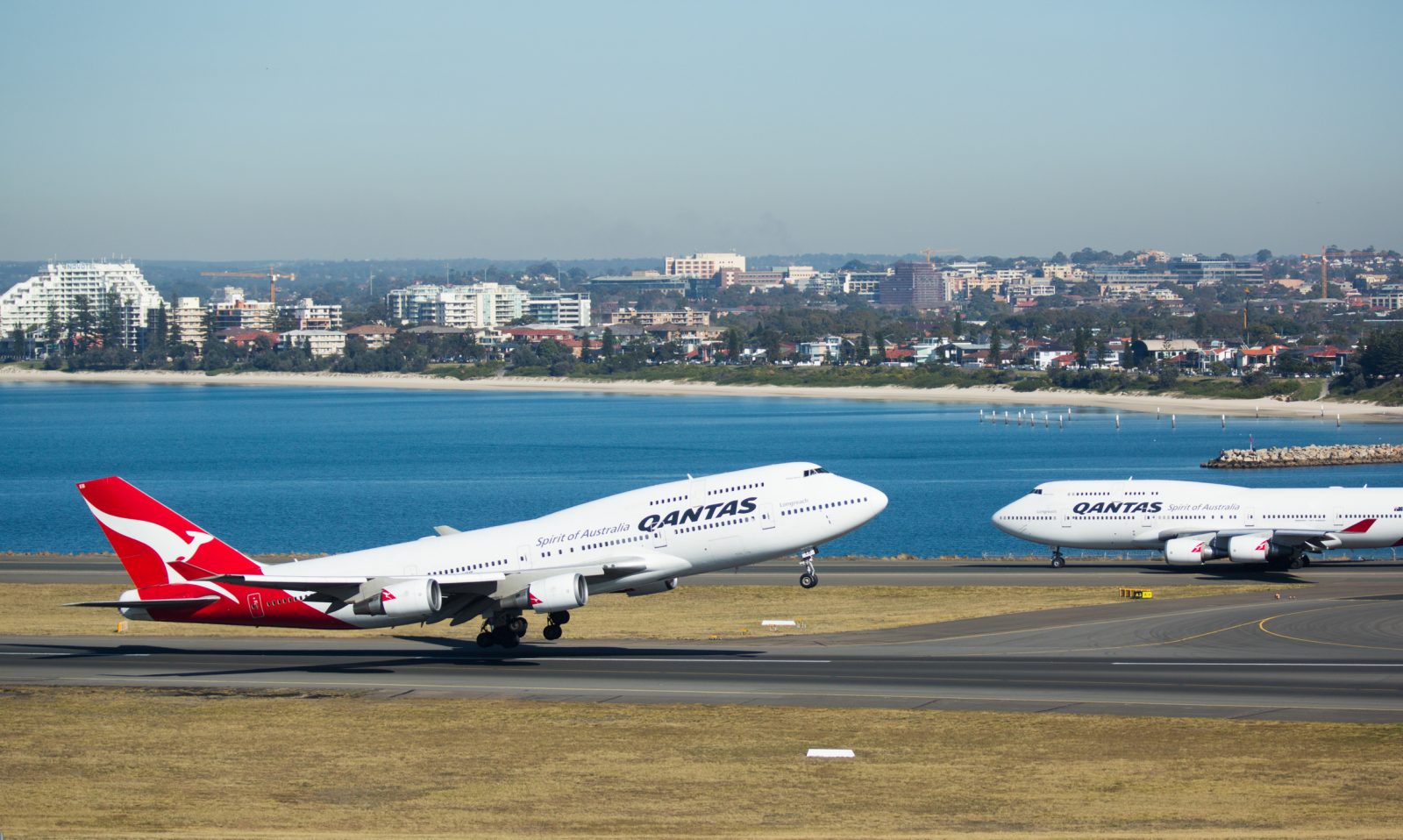 two airplanes on a runway next to a body of water