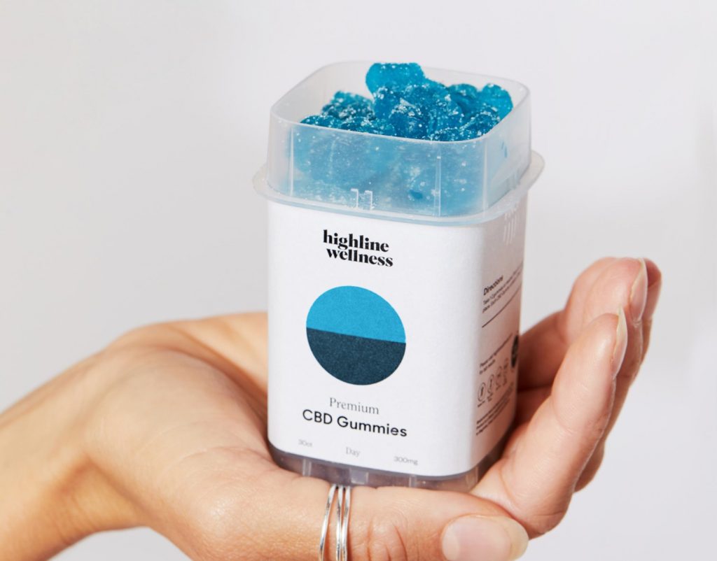 a hand holding a container of blue gummy candy