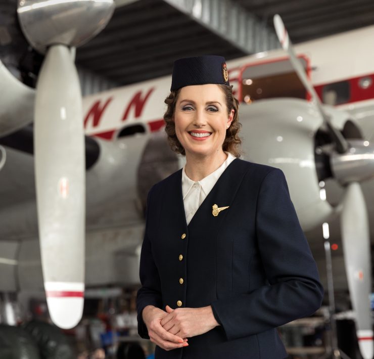 a woman in uniform standing in front of a plane