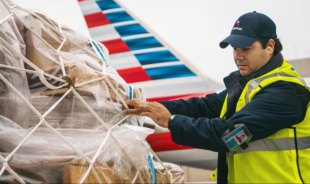 a man in a vest and hat holding a plastic bag