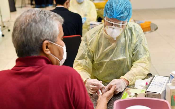 a man wearing a mask and gloves while another man in a red shirt