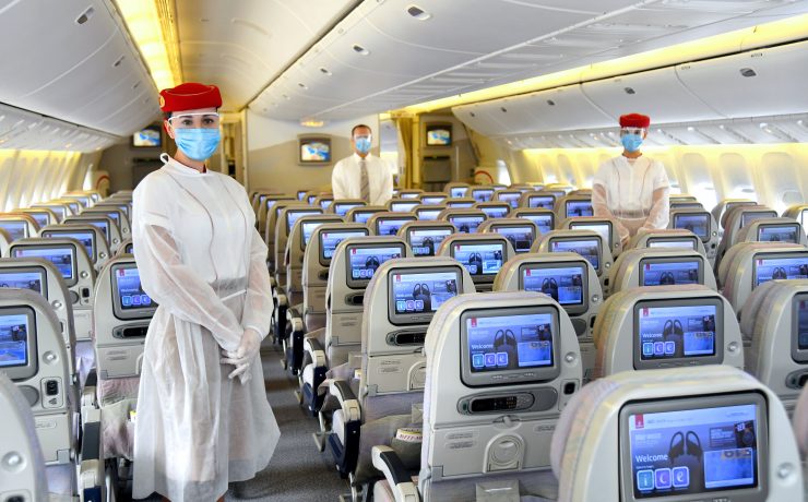 a group of people wearing face masks and standing in an airplane