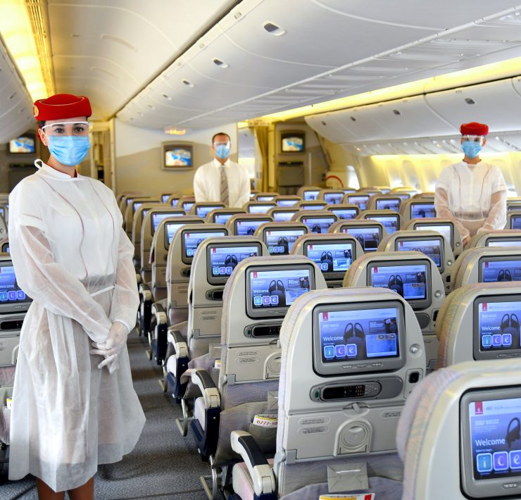 a group of people wearing face masks and standing in an airplane
