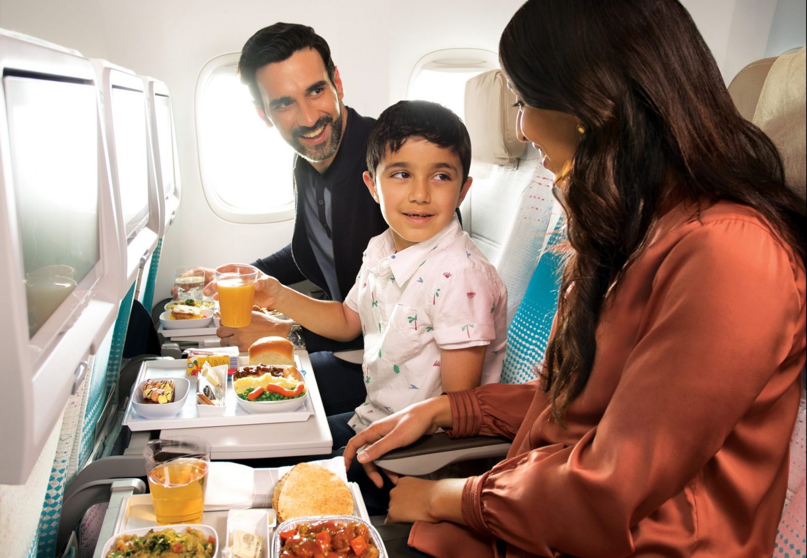 a man and woman sitting in an airplane eating food