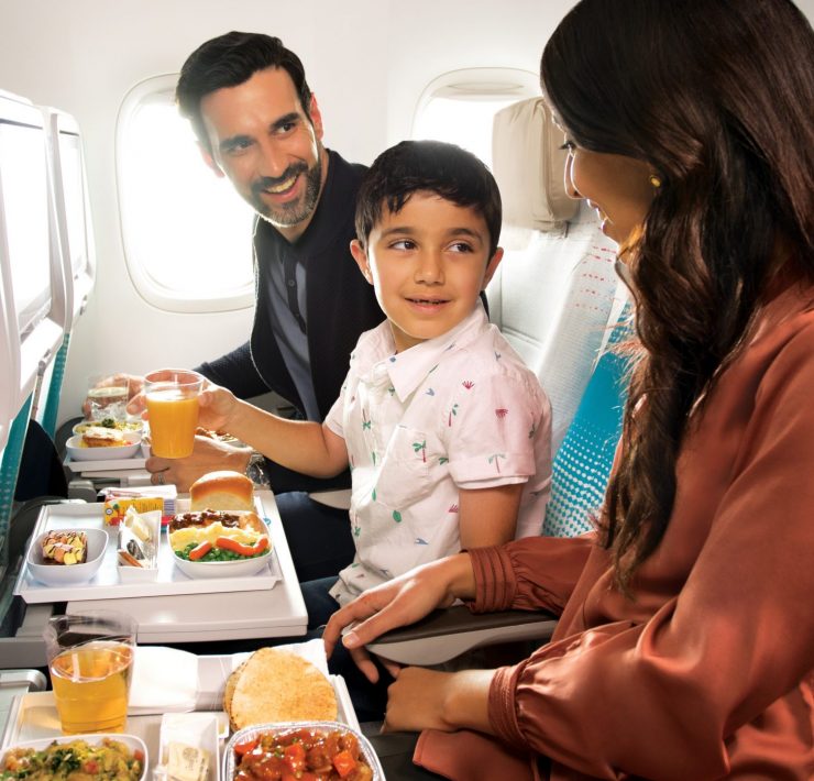 a man and woman sitting in an airplane eating food