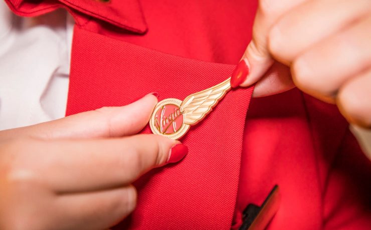 a person putting a gold pin on a red shirt