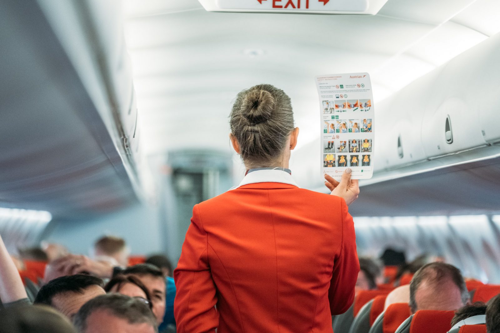 flight attendant holding up safety card in front of passengers