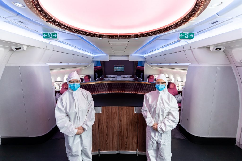 two people in white protective suits and masks in a plane