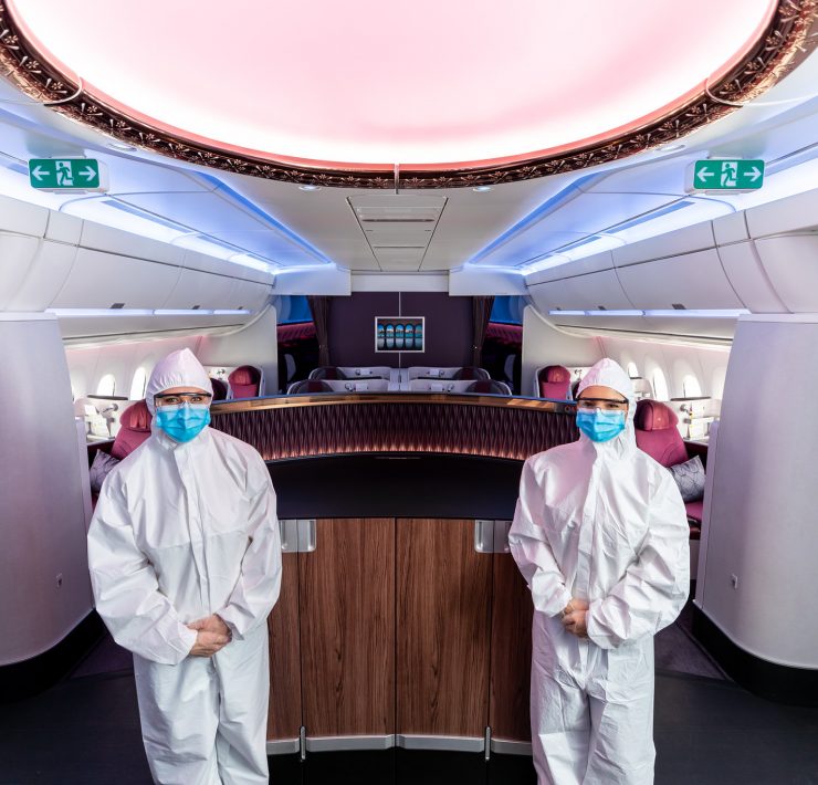 two people in white protective suits and masks standing in a plane