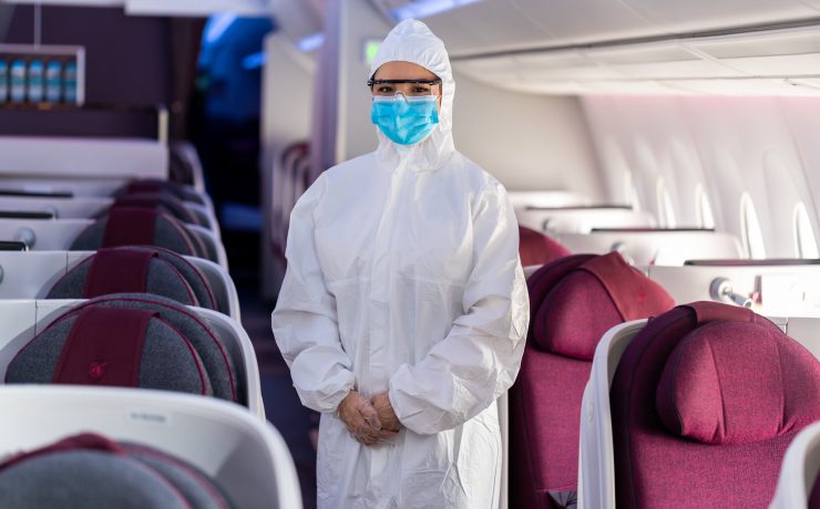 a person in a white protective suit and mask standing in an airplane