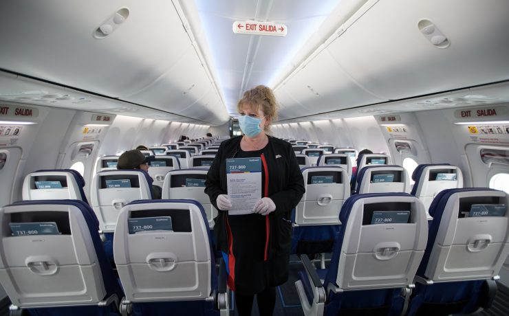 a woman wearing a mask holding a sign in an airplane