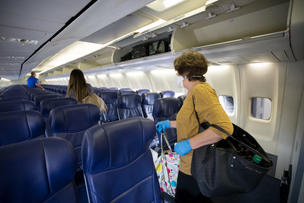 a woman in a mask and gloves on an airplane