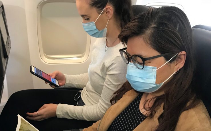 two women wearing face masks and looking at a phone