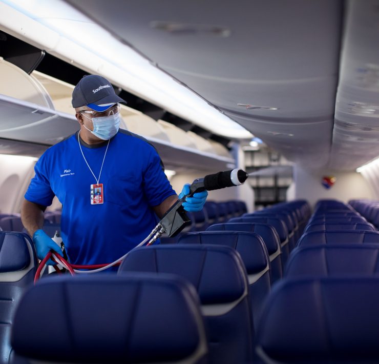 a man wearing a mask and gloves spraying a hose on an airplane