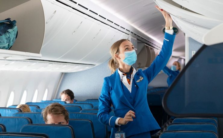 a woman wearing a mask and standing in an airplane