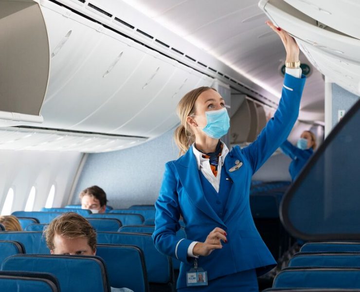 a woman wearing a mask and standing in an airplane