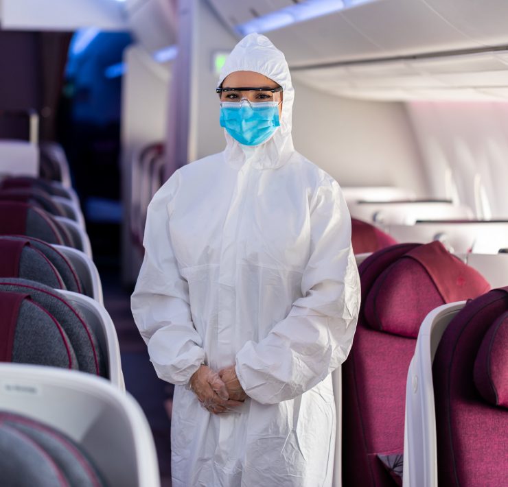 a person in a white protective suit and mask standing in an airplane