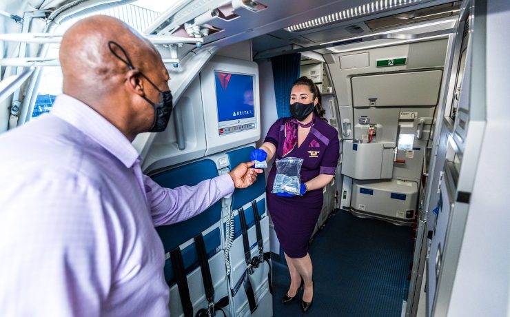 a woman wearing a face mask and holding a bag in a plane