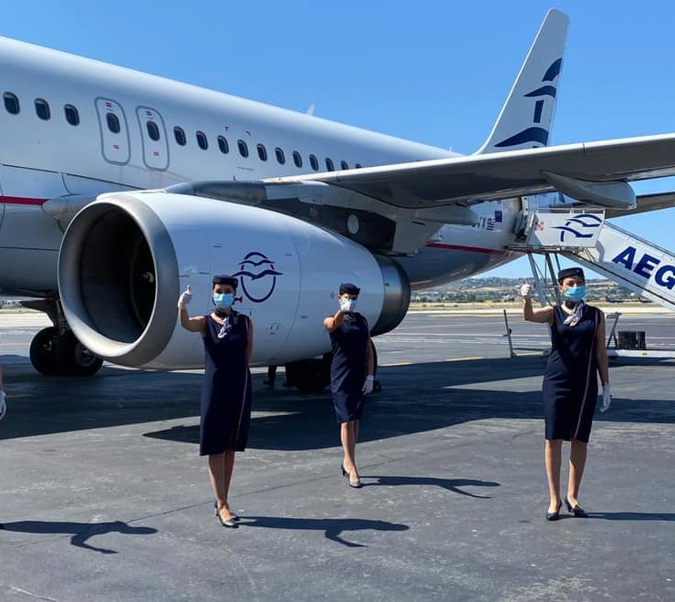a group of women wearing face masks standing in front of an airplane