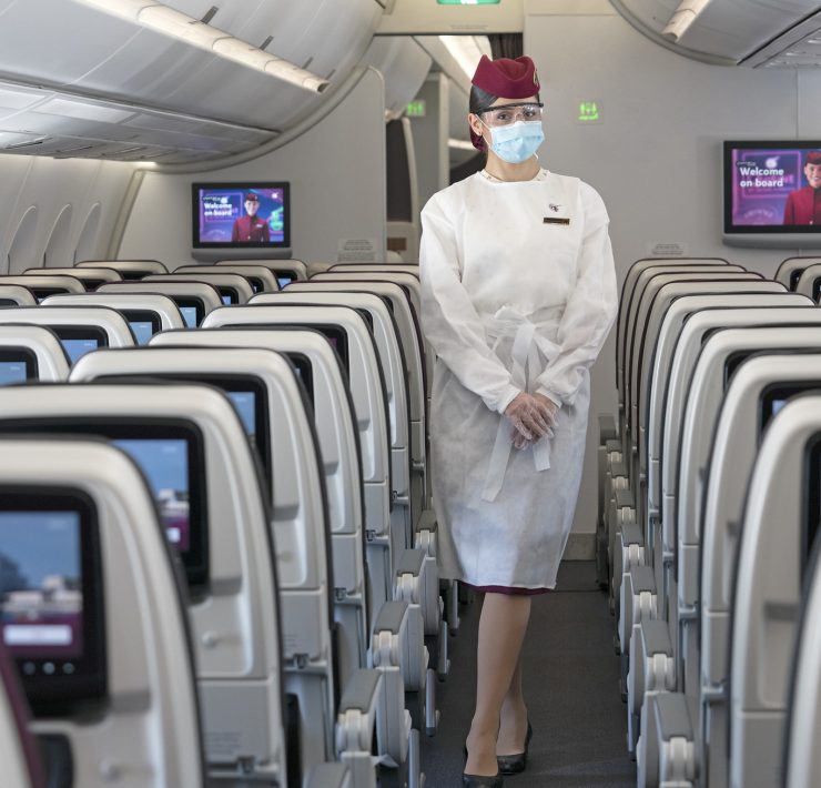 a woman wearing a mask and standing in an airplane