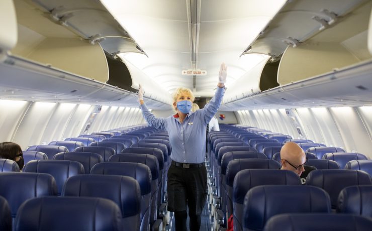 a woman wearing a mask and standing in an airplane