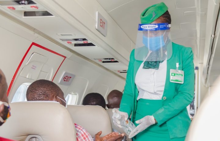 a woman wearing a face shield and gloves and a mask on a plane