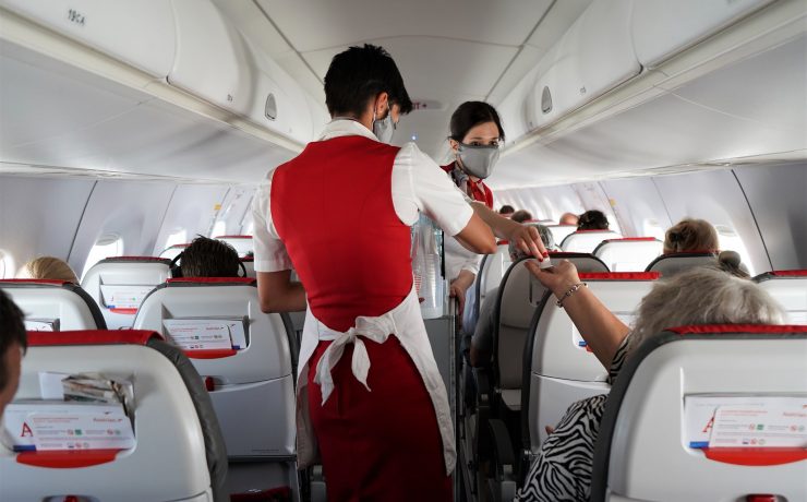 a flight attendant giving a hand sanitizer to a woman