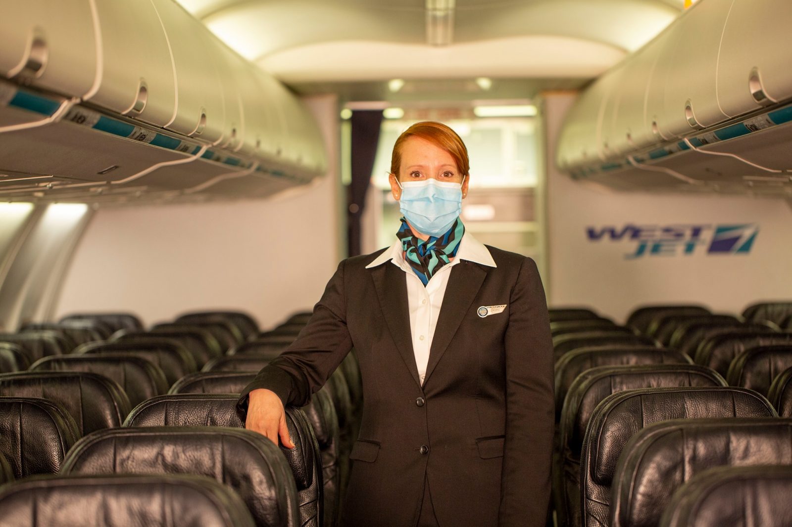 a woman wearing a mask and standing in a plane