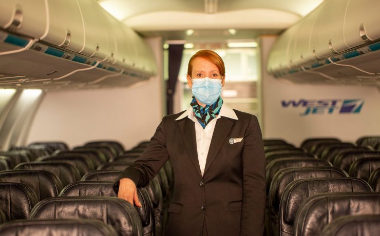 a woman wearing a mask and standing in a plane