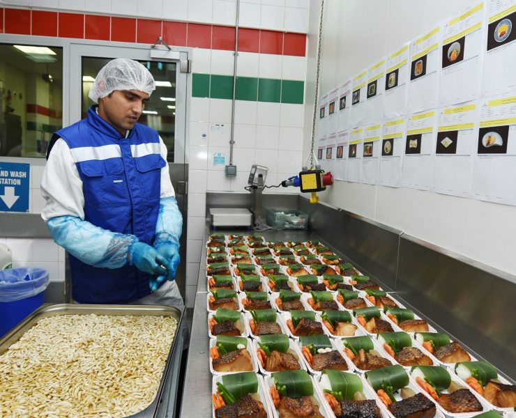 a man in a blue uniform standing in a kitchen with food