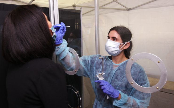 a woman wearing surgical gown and gloves holding a needle