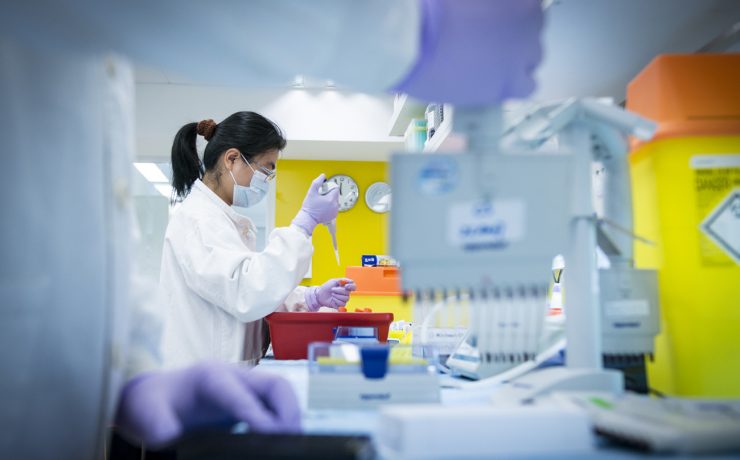 a woman in a lab coat and mask holding a dropper