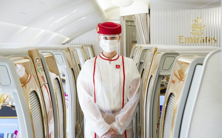 a person in a white suit and face mask standing in a row of chairs
