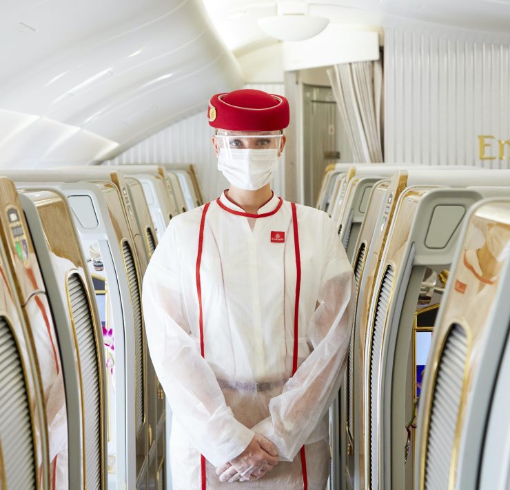a person in a white suit and face mask standing in a row of chairs