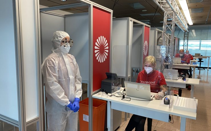 people in protective gear and goggles standing in a room with a woman in a mask
