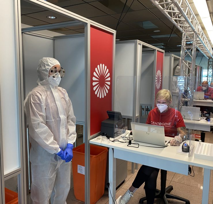 people in protective gear and goggles standing in a room with a woman in a mask
