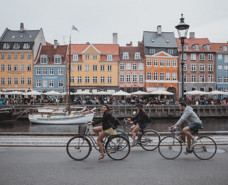 a group of people riding bicycles on a street with buildings in the background