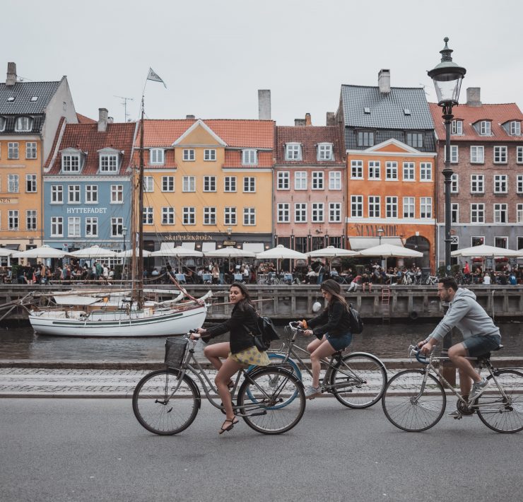 a group of people riding bicycles on a street with buildings in the background