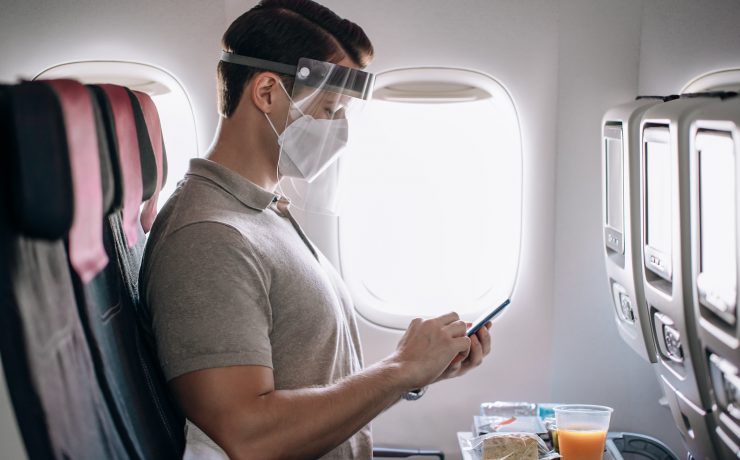 a man wearing a face mask and a face shield while using a phone