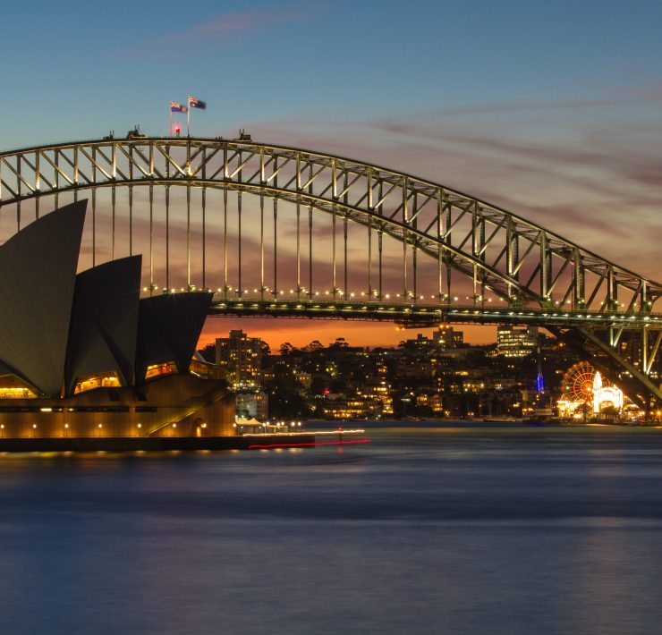 Sydney Harbour Bridge over water with a building and a ferris wheel