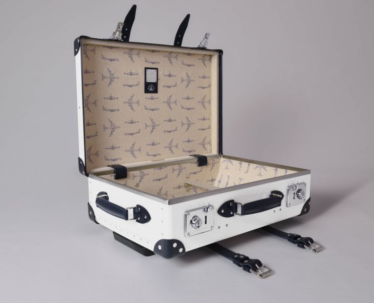 a white suitcase with black handles and a black strap